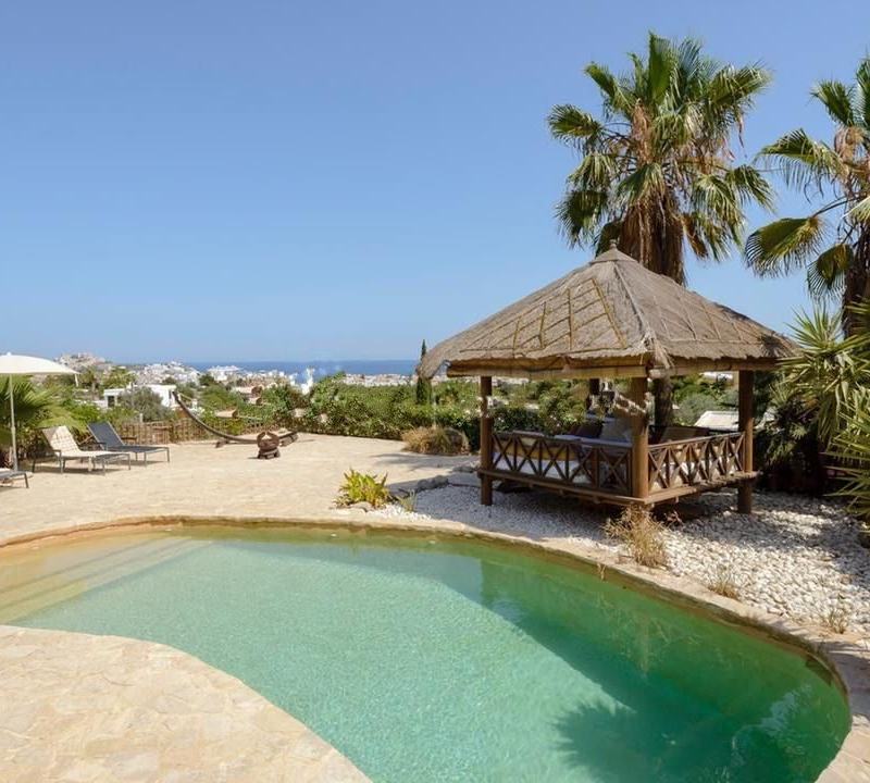 Piscina a forma di fagiolo e terrazza in pietra con vista sul mare e sulla città in lontananza