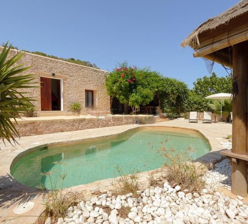 Stone facade of the villa beside the private pool and thatched chill-out gazebo