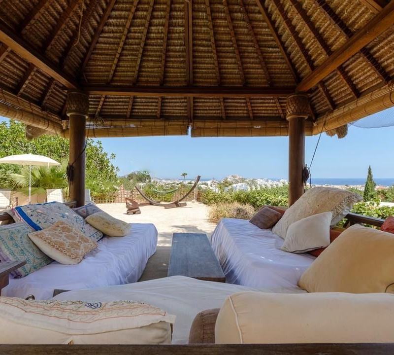 View from inside the thatched gazebo looking over daybeds towards the distant town