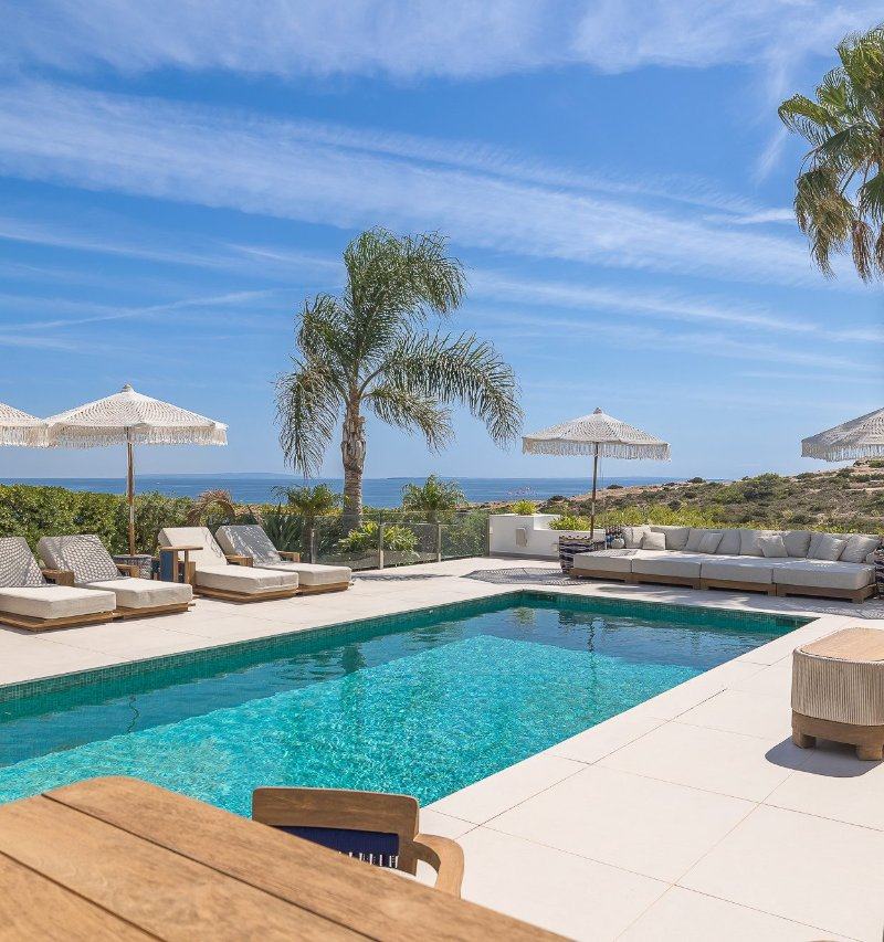 Swimming pool terrace featuring sun loungers, a large outdoor sofa, and sea views.