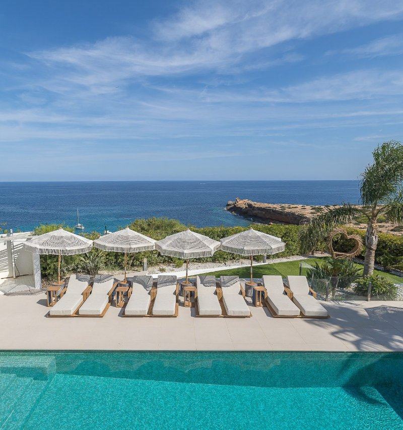 Eight sun loungers and four fringed umbrellas on a terrace facing the ocean.